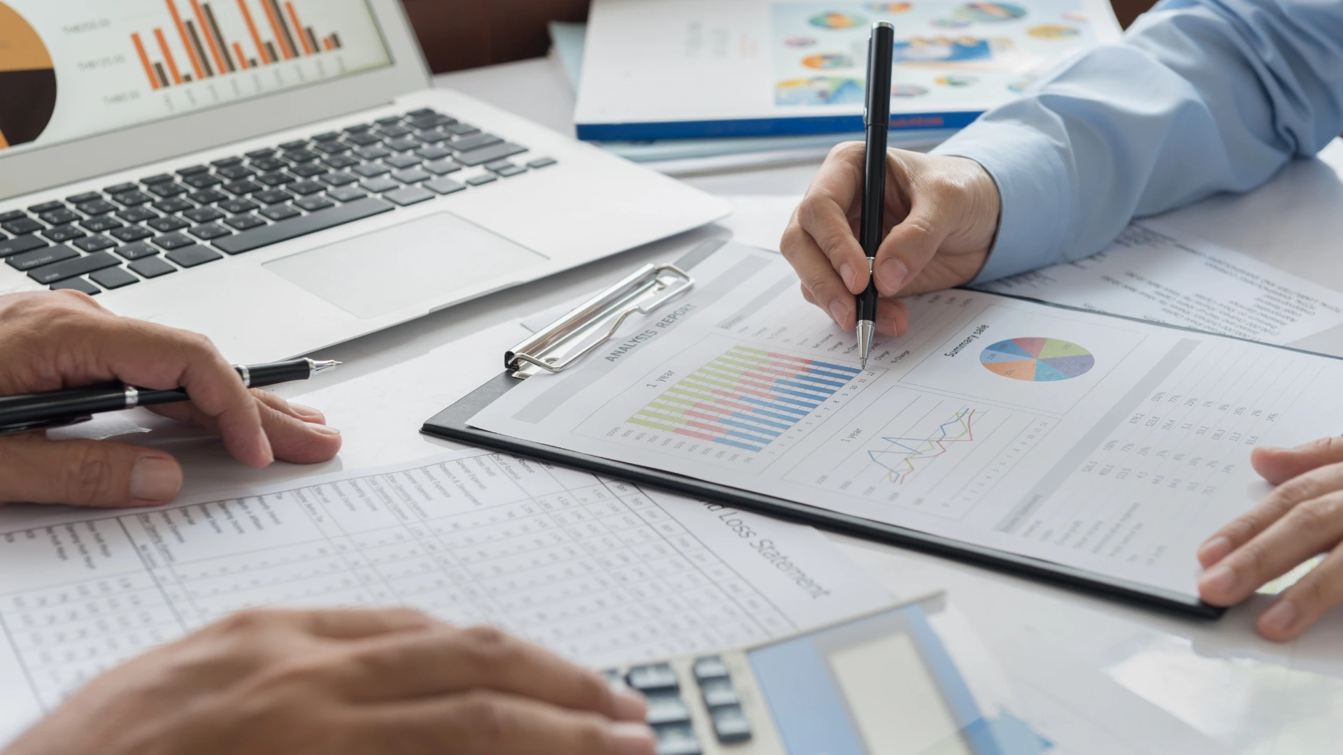 Especialista financiero señalando gráficos de rendimiento y rentabilidad empresarial en una computadora.